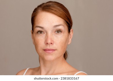 Portrait of caucasian middle aged woman of 40s looking at camera on gray background - Powered by Shutterstock