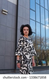 portrait of a caucasian model, brunette in a black and white elegant dress with a luxury bracelet, looking away from camera, elegance, near office center building, urban style look - Shutterstock ID 1338671858