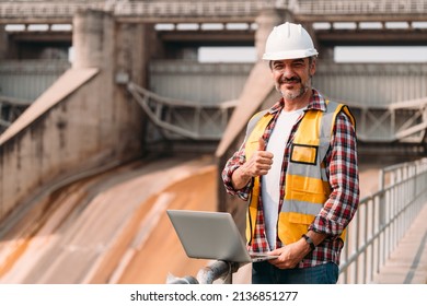 Portrait Of Caucasian Old Man Engineer Wearing Hardhat And Safety Jacket Looking At The Camera  And Smiling With Optimistic Cheerful. Confident Senior Man With Positive Mindset At Working Site Area.