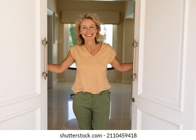 Portrait of caucasian senior woman smiling while opening the front door of her house. home welcome concept, unaltered. - Powered by Shutterstock