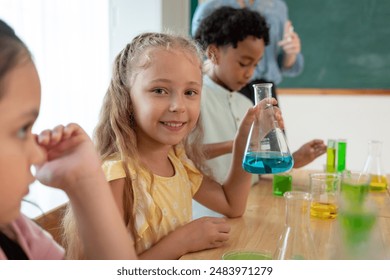 Portrait of Caucasian student learning in classroom at elementary school. Adorable young schoolgirl looking at camera study science and doing chemistry experiment with fun activity at kindergarten. - Powered by Shutterstock