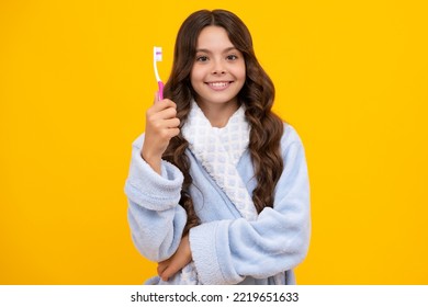 Portrait Of Caucasian Teen Girl Holds A Toothbrush Brushing Her Teeth, Morning Routine, Dental Hygiene, Isolated On Yellow Background.