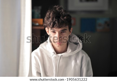 Similar – Portrait of a smiling Caucasian man in his 20s wearing a sweatshirt against a dark background.