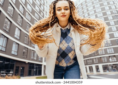 Portrait of Caucasian white young full-figured teenager woman showing long blond braided hairstyle with modern building on background. - Powered by Shutterstock