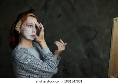 Portrait of a Caucasian woman applying anti-aging cosmetics to her face in front of a mirror. High resolution photos - Shutterstock ID 1981347881