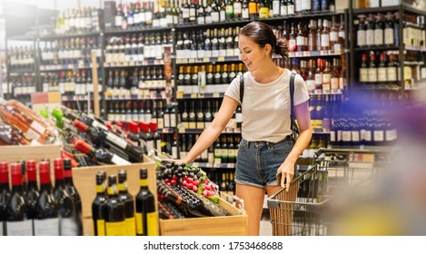 Portrait Of Caucasian Woman Buying At Wine Grocery Store. Happy Hispanic Girl Shopping In Supermarket Reading Product Information. Costumer Buying Alcoholic Spirits At The Market, Woman Lifestyle.