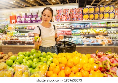 Portrait Of Caucasian Woman Looking At Product At Grocery Store. Happy Hispanic Girl Shopping In Supermarket Chose Green Organic Vegetable. Costumer Buying Food At The Market, Woman Lifestyle Concept.