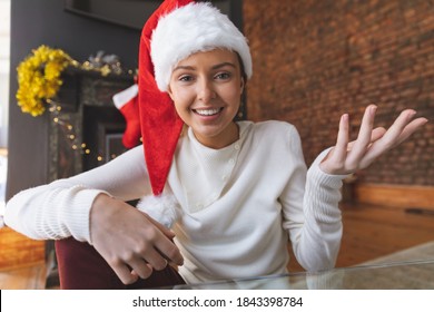 Portrait of Caucasian woman spending time at home at Christmas, wearing a Santa hat and making a video call, smiling and gesturing. Social distancing during Covid 19 Coronavirus quarantine lockdown. - Powered by Shutterstock