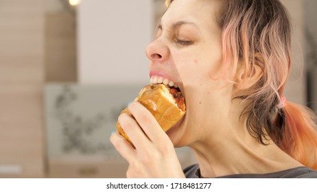 Portrait Of Caucasian Young Beautiful Woman Greedily Eagerly Eating Food During Quarantine Due To Coronavirus. Charming Happy Hungry Woman On Diet Laugh And Biting Off Big Meat Pie. Close Up.