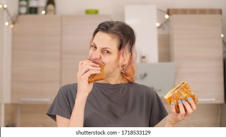 Portrait Of Caucasian Young Beautiful Woman Greedily Eagerly Eating Food During Quarantine Due To Coronavirus. Charming Happy Hungry Woman On Diet Laugh And Biting Off Big Meat Pie. Close Up.