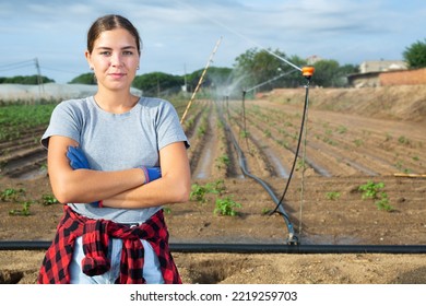 Portrait of caucasian young woman agriculturist standing on vegetable plantation during irrigation with arms crossed. - Powered by Shutterstock