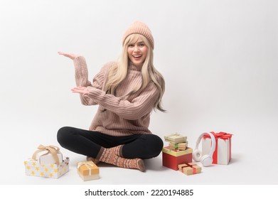 Portrait of Caucasian young woman wearing sweater holding gifts box  over white background