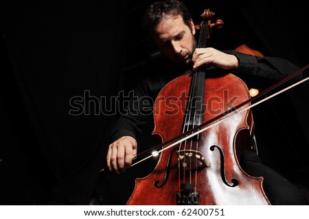 Portrait of cellist playing classical music on cello on black background. Copyspace.