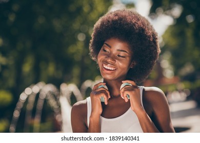 Portrait of charming afro american girl touching her wireless headset in summer town forest park with fountains - Powered by Shutterstock