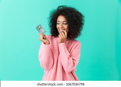 Portrait Of Charming American Woman 20s With Afro Hairstyle Holding Plastic Credit Card With Pleasure Isolated Over Blue Background