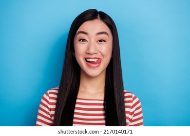 Portrait of charming cheerful indonesian girl tongue lick teeth isolated on blue color background