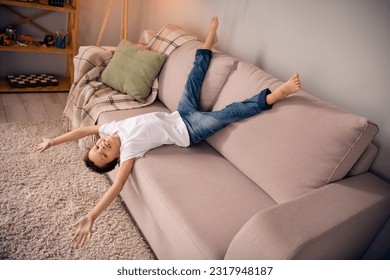 Portrait of charming happy small boy lying couch upside down playful wear white shirt stylish child room interior furniture decoration - Powered by Shutterstock