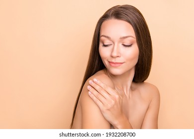 Portrait of charming person look arm touch shoulder applying cream wear nothing isolated on beige color background