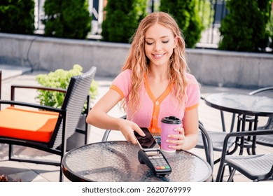 Retrato de la encantadora chica positiva beber café en la mañana fin de semana sin efectivo pago café restaurante exterior