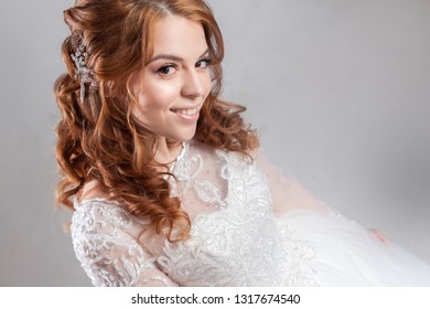 Portrait of a charming red-haired bride, Studio, close-up. Wedding hairstyle and makeup. Young woman in luxurious wedding dress