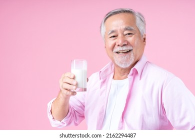 Portrait Charming Retired Asian Senior Man Drinking Glasses Of Milk, Happiness Elder Man Wearing Shirt Pink Holding Milk In Hand Enjoying Drink Milk For Health And Bone Health Pink Background.