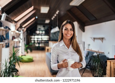 Portrait of a charming young woman holding a mug and looking at camera in modern loft. - Shutterstock ID 1222971196