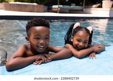 Portrait of cheerful african american siblings laughing while relaxing at poolside in resort. Unaltered, family, love, togetherness, childhood, swimming pool, enjoyment and weekend concept. - Powered by Shutterstock