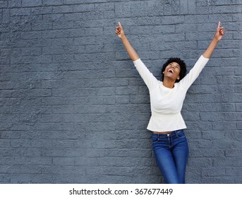 Portrait of a cheerful african woman with hands raised pointing up
