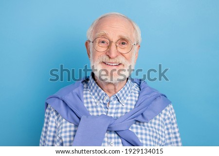 Portrait of cheerful aged man beaming smile look camera tied on neck pullover isolated on blue color background
