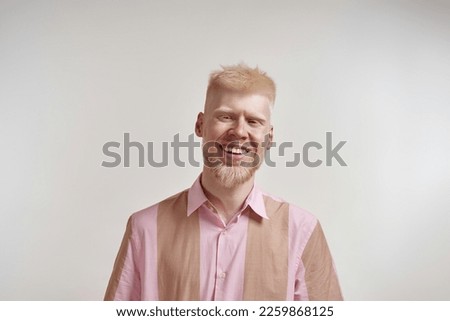 Portrait of cheerful albino caucasian guy looking at camera. Young bearded blonde man of zoomer generation wearing t-shirt. Isolated on white background. Studio shoot. Copy space