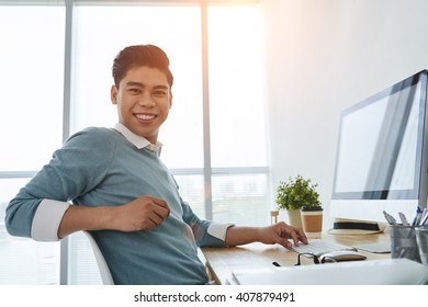 Portrait of cheerful Asian businessman at his workplace - Shutterstock ID 407879491