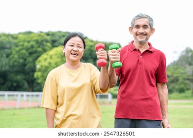 portrait cheerful asian senior couple holding dumbbells posing to camera,happy elderly enjoy doing exercise in the stadium,family healthy lifestyle, - Powered by Shutterstock