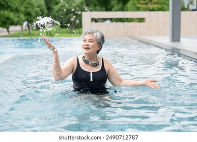 portrait cheerful asian senior woman smiling happily while splashing water in pool,elderly people holidays on summertime - Powered by Shutterstock