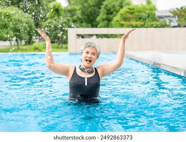 portrait cheerful asian senior woman smiling happily while splashing water in pool,elderly people holidays on summertime - Powered by Shutterstock