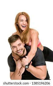 Portrait of cheerful athletic man carrying his laughing woman on back