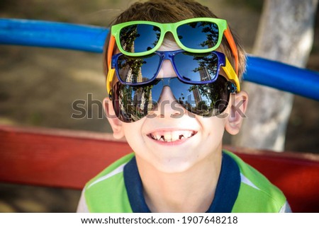 Portrait of a cheerful boy child in several sunglasses outdoors. Beauty, summer casual fashion. Optics for children. Sun protection.