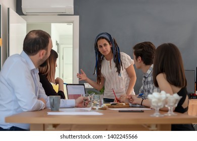 Portrait of cheerful business woman standing in modern creative office with employees smiling