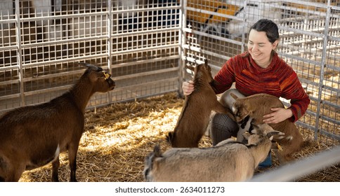 Retrato de la mujer adulta casual alegre que juega con las cabras lindas en el puesto del zoológico que acaricia en día soleado.