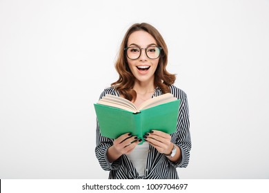 Portrait of a cheerful casual girl holding book and laughing isolated over white background - Shutterstock ID 1009704697