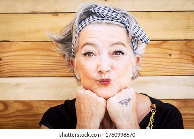 Portrait of cheerful caucasian senior happy woman with wood background - alternative and young old female smile and enjoy - tatooed skin for diversity concept and age - youthful lifestyle