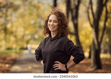 Portrait of cheerful caucasian woman wearing sports clothes and standing in the autumn park - Shutterstock ID 2340561063