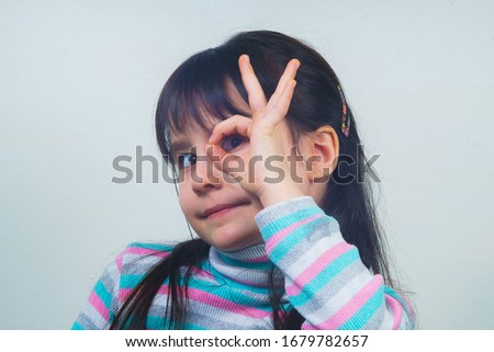 Portrait of a cheerful child with long hair and a striped sweater. girl fooling around