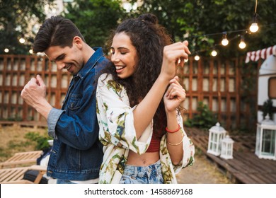 Portrait Of Cheerful Couple Man And Woman Smiling While Dancing Together Near House On Wheels Outdoors