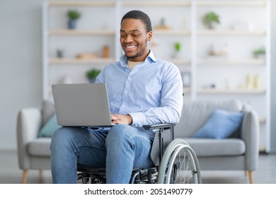 Portrait of cheerful disabled young black man in wheelchair using laptop for remote job at home. Happy black guy with physical disability having online work during covid pandemic - Powered by Shutterstock