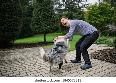 Portrait Of Cheerful Down Syndrome Adult Man Playing With Dog Outdoors In Backyard.