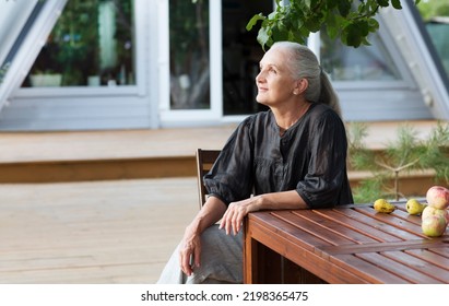 portrait of a cheerful elderly woman in the garden about her home. Enjoying the little things. spends time in nature in summer - Powered by Shutterstock