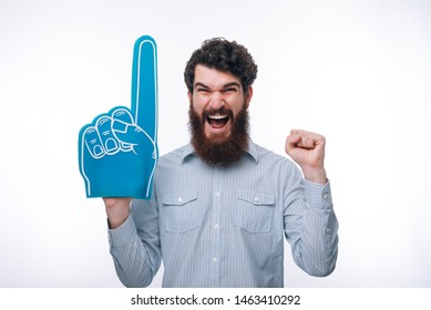 Portrait of a cheerful excited  man with a foam finger shouting and looking at camera 