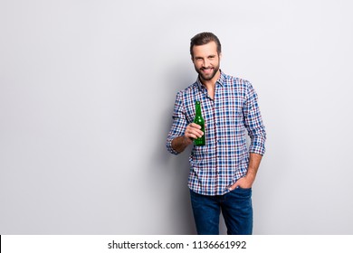 Portrait of cheerful excited relaxed carefree guy drinking beer from bottle holding in hand wearing checkered blue shirt denim jeans isolated on gray background copy-space
