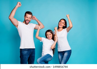 Portrait Of Cheerful Family Having Brunette Hair Raising Fists Screaming Yeah Celebrating Victory Wearing White T-shirt Denim Jeans Isolated Over Blue Background