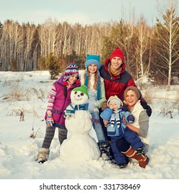 Portrait Of A Cheerful Family With Snowman. Happy Children And Parents In The Winter Outdoors